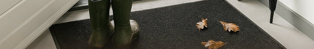 Stimmungsvolles Foto von schmutzigen Stiefeln auf einer Fußmatte und einer Außenfußmatte